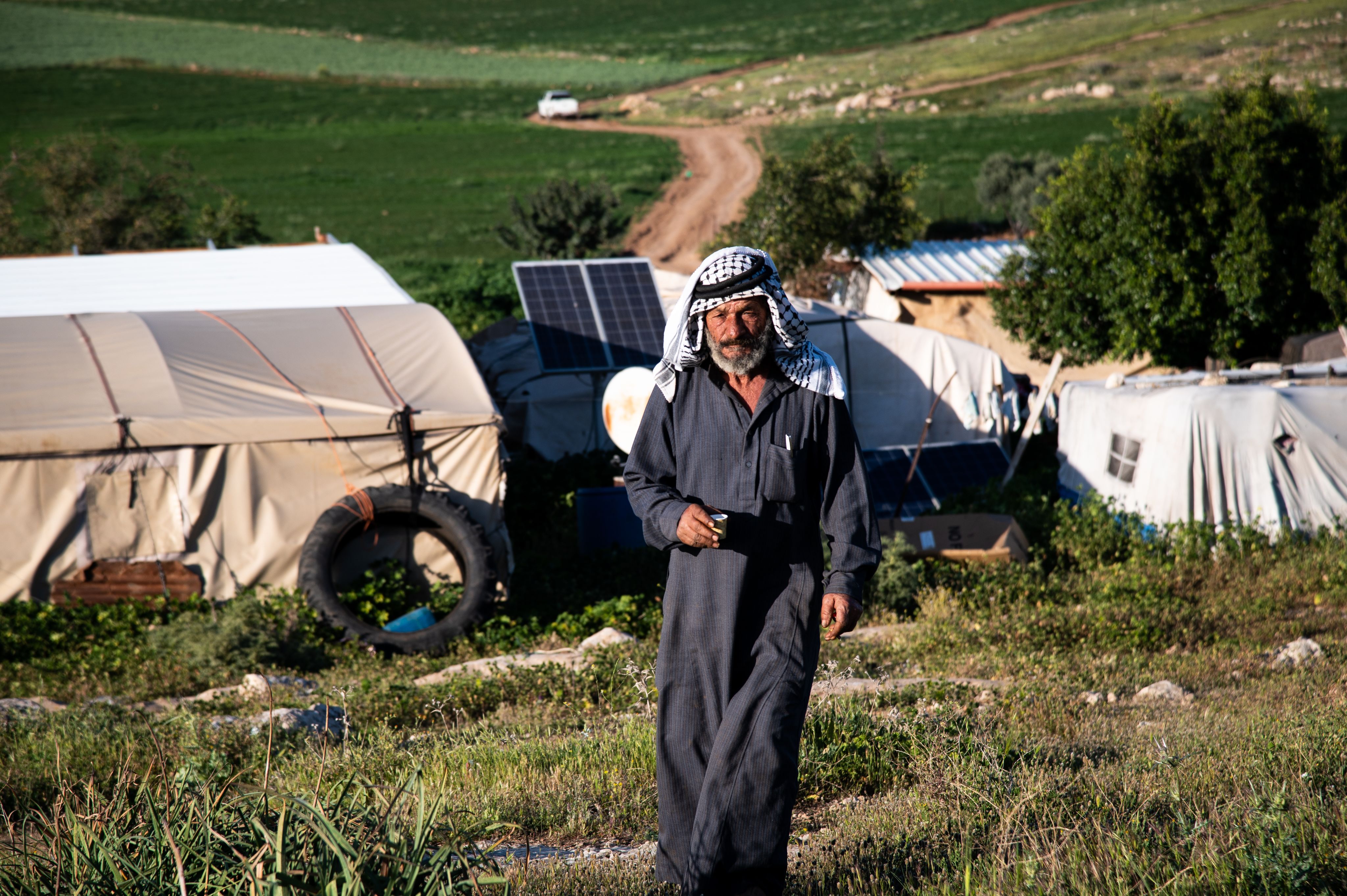 Abu Saqqa går opp en ås, bak ham er hans teltleir